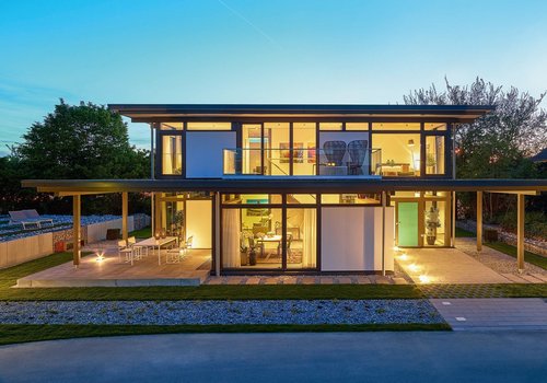 Moderne Architektur im Abendlicht Zweistöckiges Wohnhaus mit großflächigen Fenstern und Garten