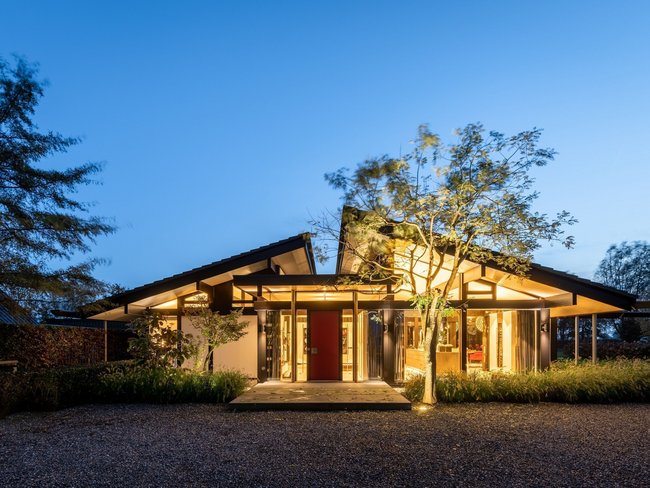 Bungalow mit organischen Formen und großen Glasflächen in schöner Landschaft