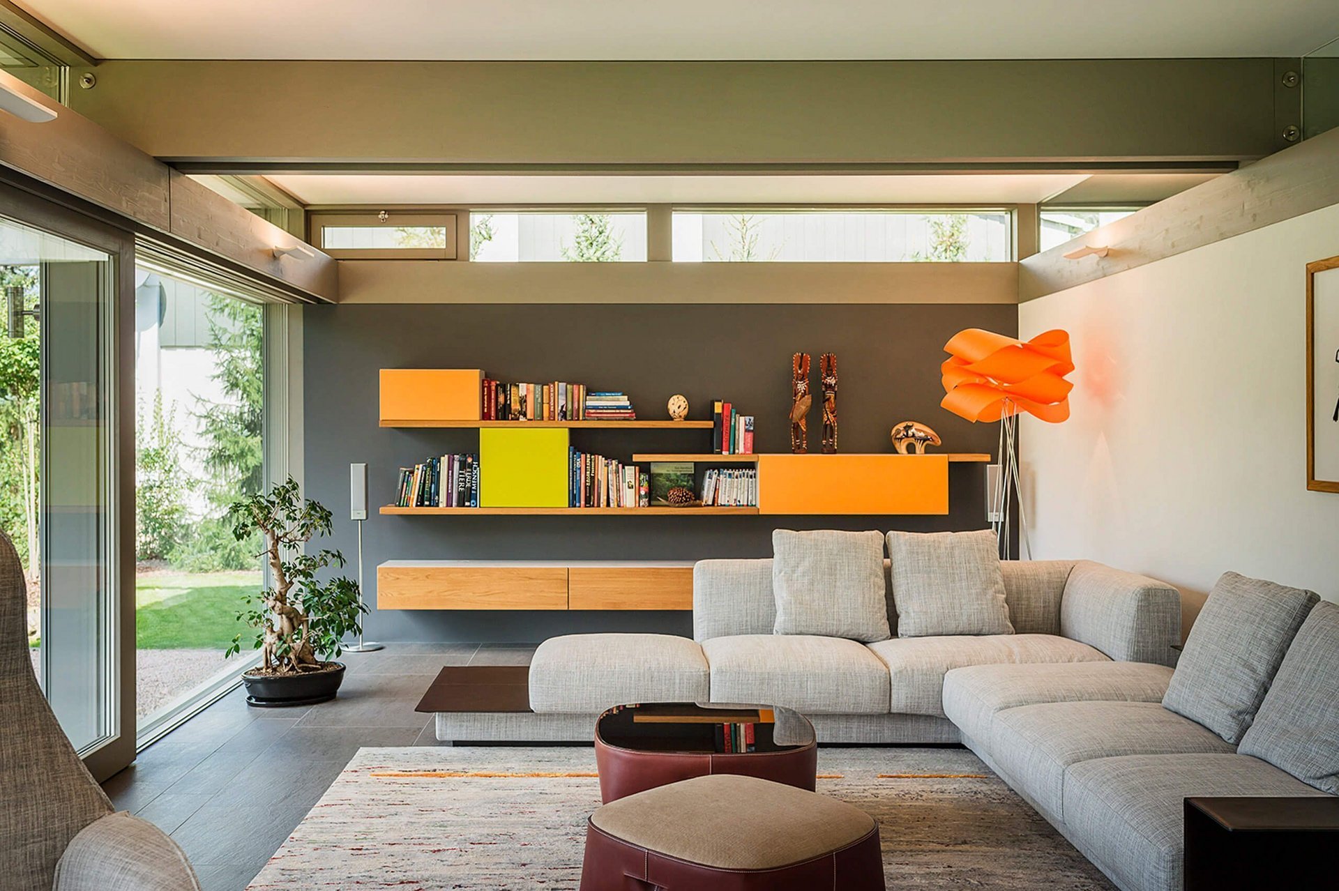 Helles Wohnzimmer mit minimalistischem Sofa und bunten Regalen
