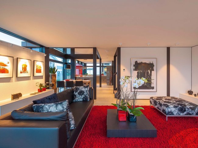 Ein eleganter Wohnbereich mit schwarzem Sofa und rotem Teppich.