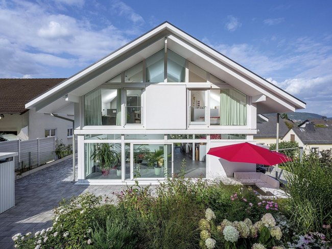 Das Architektenhaus zeigt eine moderne Fassade mit großen Fenstern und einem Patio