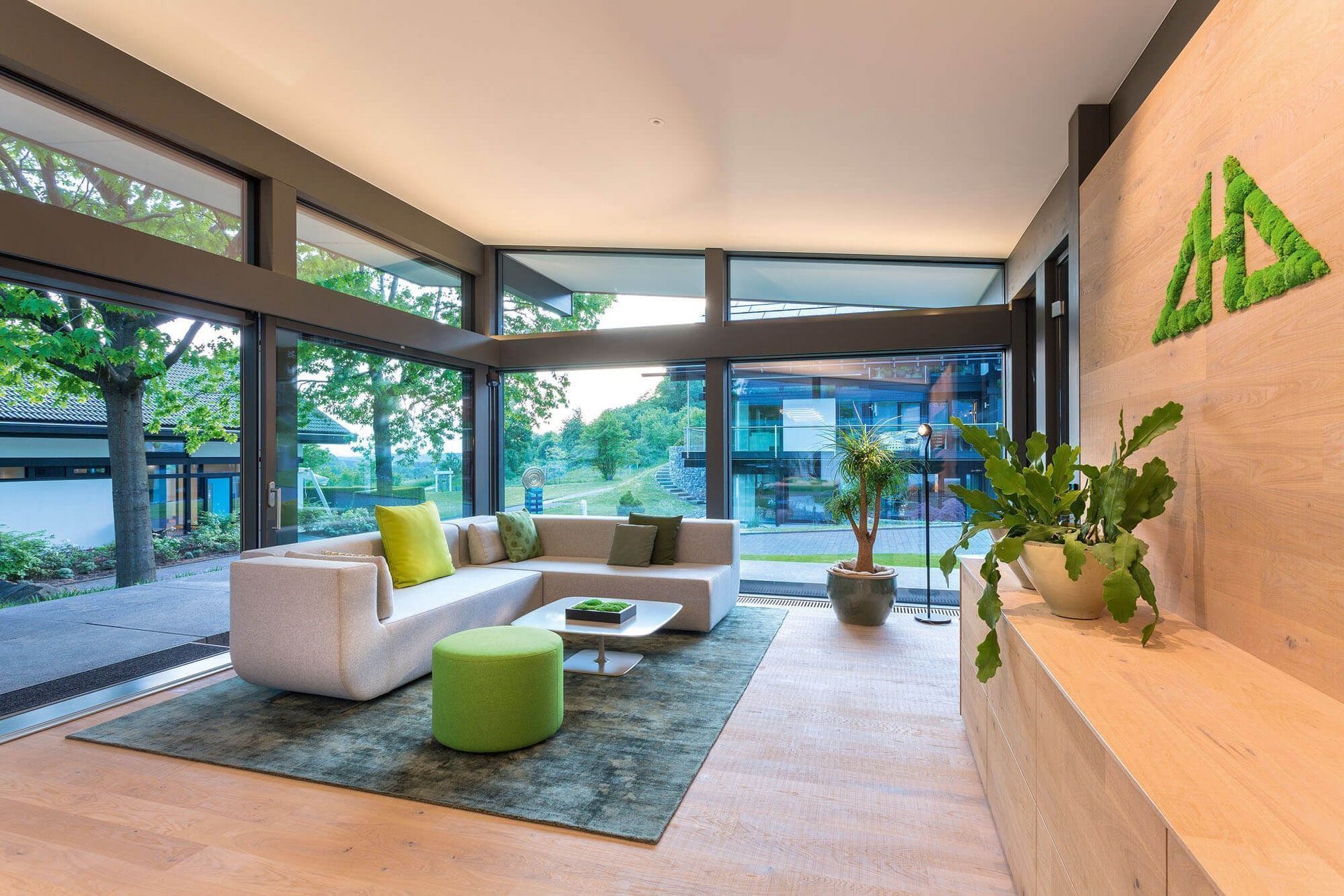 Helles Wohnzimmer mit Sofa, Pflanzen und großen Fenstern