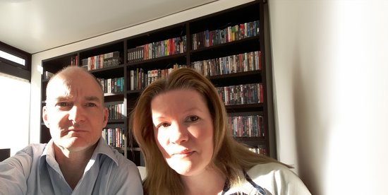 Selfie in a room with bookshelves A man and a woman posing for a selfie in a well-lit room