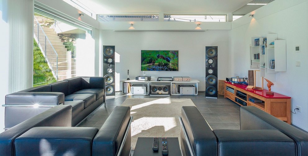 Spacious living room featuring black sofas and a large TV