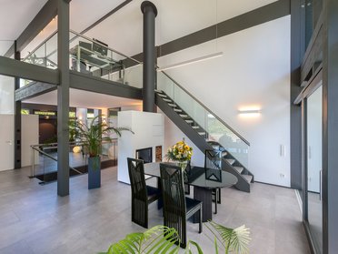 Geräumiger Wohnraum mit Treppe, Esstisch und Pflanzen.