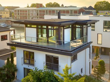 Bestandshaus mit HUF Aufstockung Moderne Architektur eines aufgestockten Hauses mit Glasbalkon