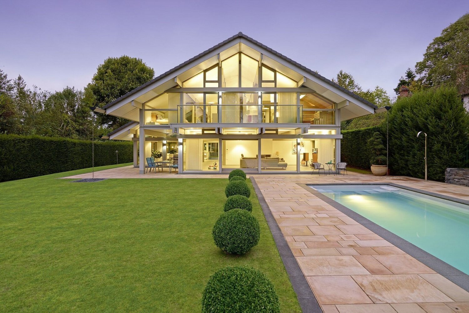 HUF HAUS mit einzigartiger Fachwerkarchitektur Moderne Villa mit Glasfront, Garten und Pool bei Dämmerung