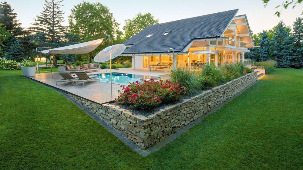 Modernes Fachwerkhaus mit Pool und Gartenlandschaft Weißes Fachwerkhaus mit Doppelpultdach umgeben von Bäumen und Garten