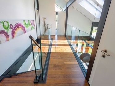 Gemütlicher Flur in einem modernen Architektenhaus Stilvoller Flur mit Glasgeländer und Holzfußboden