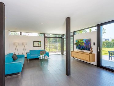 Helle Wohnzimmeransicht mit blauen Sofas und moderner Ausstattung