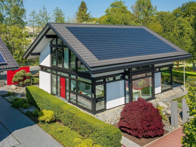 Ansicht einer modernen Villa mit Solarpanelen und gepflegtem Garten