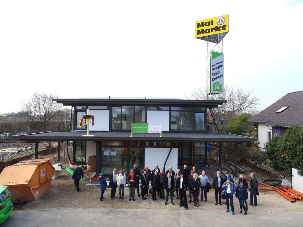 Gruppenfoto vor dem neuen Mail Markt Gebäude Menschen stehen vor einem modernen Gebäude mit Mail Markt Schild