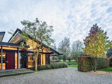 Bungalow mit organischen Formen und Glasflächen Bungalow eingebettet in eine traumhafte Landschaft mit Bäumen und Wiesen