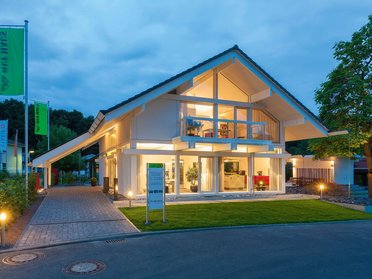 HUF Musterhaus Frankfurt weiss 16 Ein modernes Wohnhaus mit Beleuchtung und Rasenfläche.