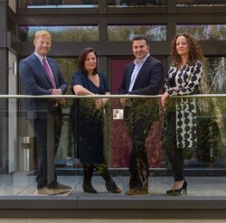 Four individuals standing on a balcony of a modern building
