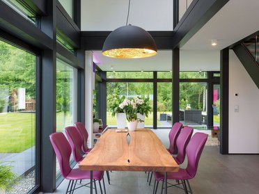 Gemütliches Architektenhaus mit stilvollem Essbereich Modernes Esszimmer mit großer Holzplatte und eleganten Stühlen