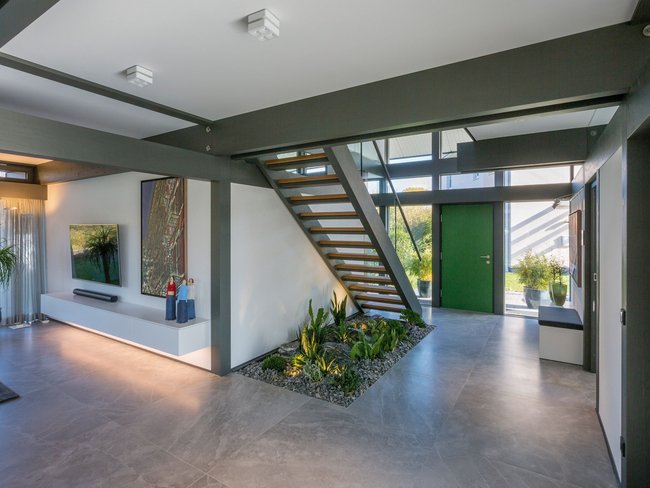 Helle Eingangshalle mit Treppe, Pflanzen und modernem Dekor