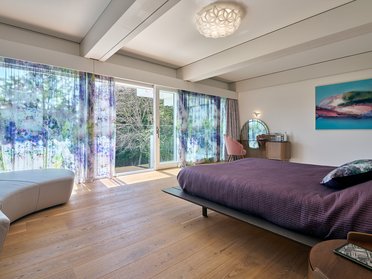 Moderne Villa mit Flachdach und lichtdurchflutetem Schlafzimmer Elegantes Schlafzimmer mit Blick auf die Natur und großzügigen Fenstern