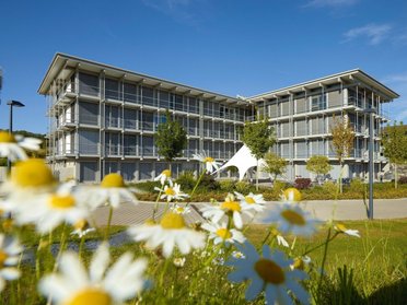 Bürogebäude HUF in der Natur Modernes Bürogebäude HUF mit Blumen im Vordergrund