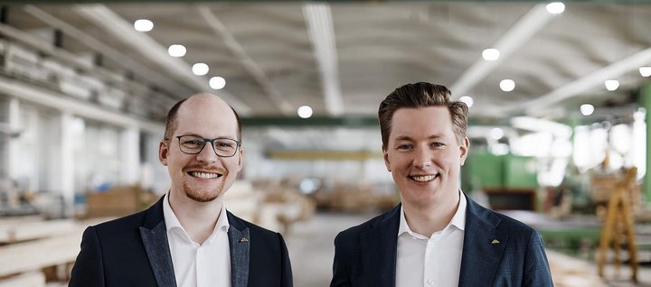 Zwei Männer stehen in einer Holzwerkstatt Freundliche Männer in Anzügen vor Holzregalen in einer Werkstatt