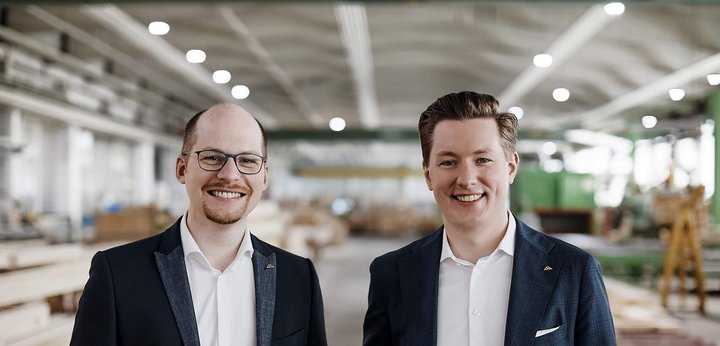 Zwei Männer stehen in einer Holzwerkstatt Freundliche Männer in Anzügen vor Holzregalen in einer Werkstatt
