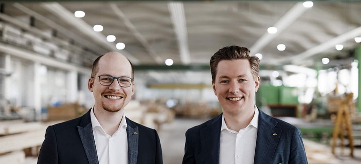 Zwei Männer stehen in einer Holzwerkstatt Freundliche Männer in Anzügen vor Holzregalen in einer Werkstatt