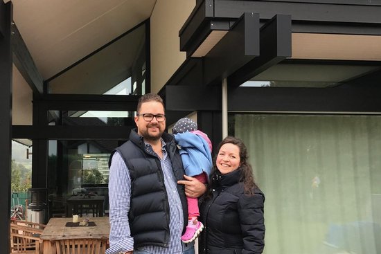Familie vor modernem Haus mit Grill im Vordergrund Familie posiert vor einem modernen Haus mit großen Fenstern