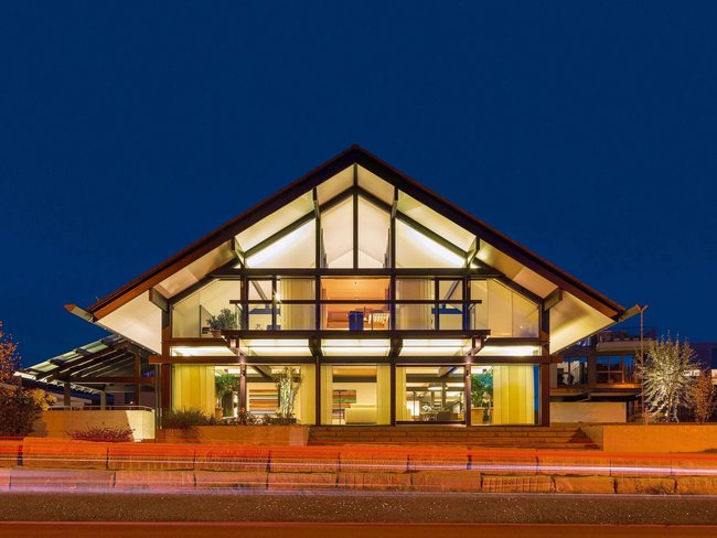 Elegantes Gebäude mit Glasfront und strukturierten Dächern bei Nacht