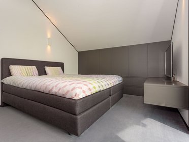 Helles und minimalistisches Schlafzimmer mit Doppelbett und TV