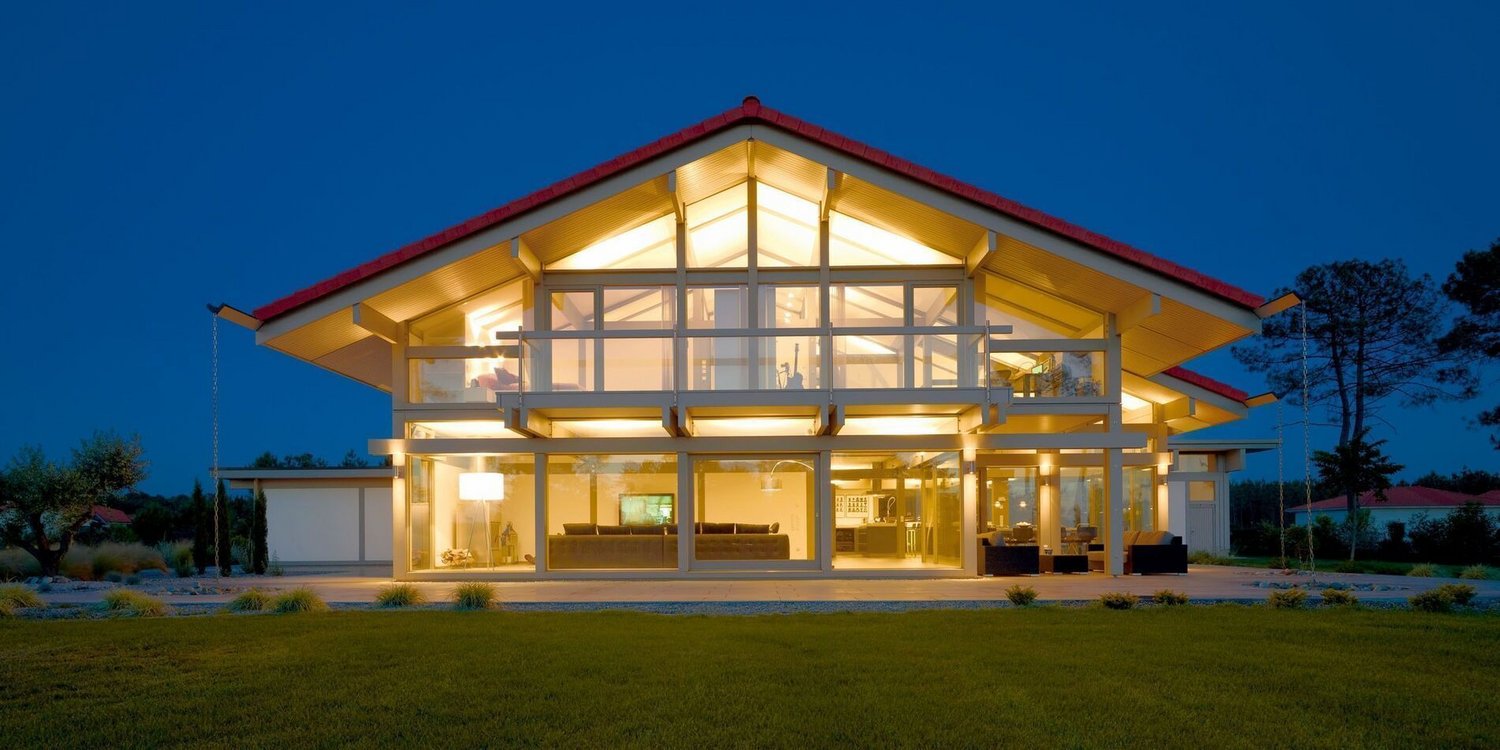 Moderne HUF Haus mit Flugzeughangar bei Nacht HUF Haus mit großen Fenstern und beleuchtetem Innenraum