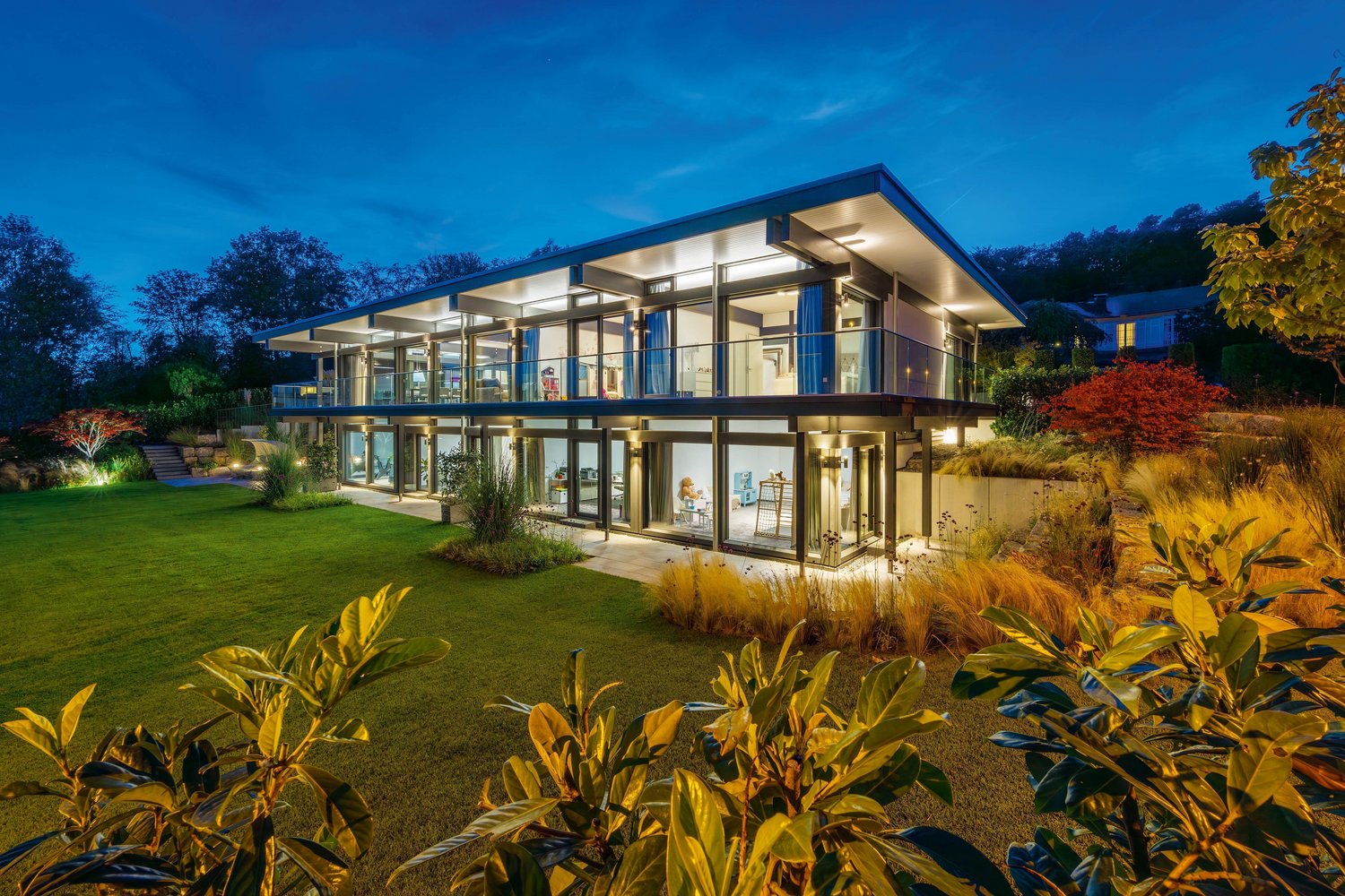 Maximale Transparenz im HUF HAUS mit Flachdach Modernes HUF Haus mit Flachdach und klaren Linien bei Nacht