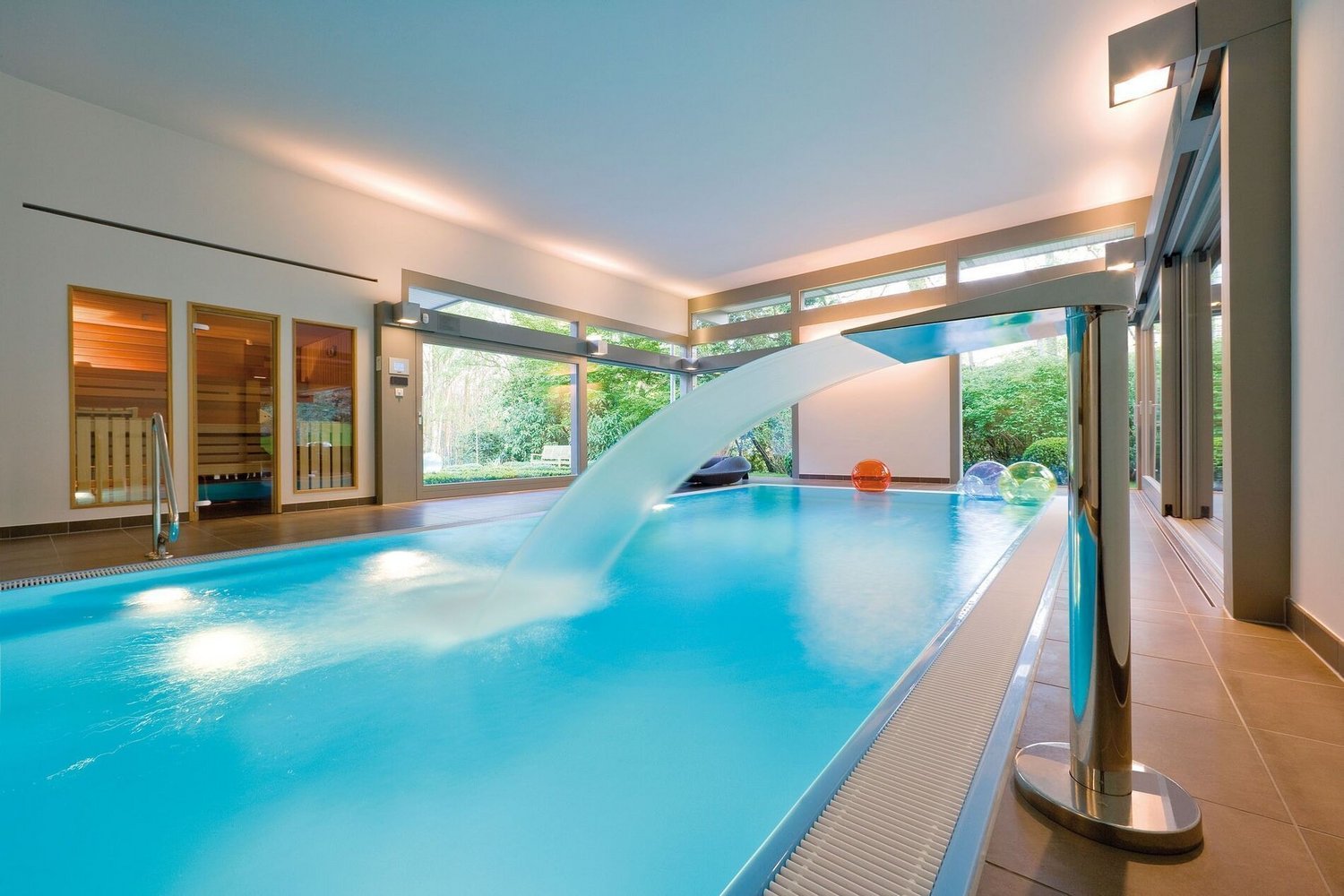 Traumhaus mit modernem Flachdach und Pool Innenansicht eines modernen Pools mit Wasserfall und Gartenblick