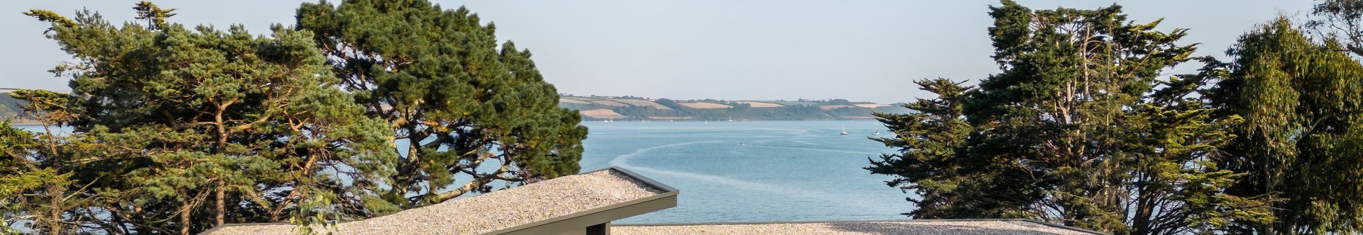 Fachwerkhaus umgeben von Blumen und Bäumen mit Blick auf das Wasser