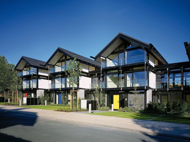 Moderne Wohngebäude mit Glasfassade und Gärten Ansicht von mehreren modernen Häusern mit schrägen Dächern und Fenstern