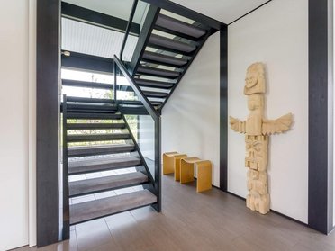 Innenansicht eines Architektenhauses mit offener Treppe und kunstvoller Holzskulptur
