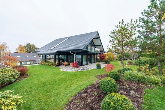 Moderne Architektur mit Gartenlandschaft Zeitgenössisches Haus umgeben von grünem Garten und bunten Pflanzen