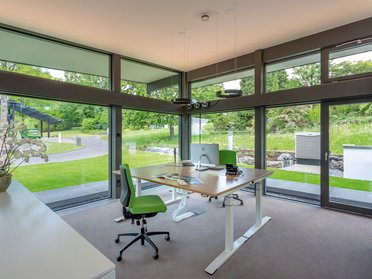Helles Büro mit grüner Einrichtung und Blick auf die Natur
