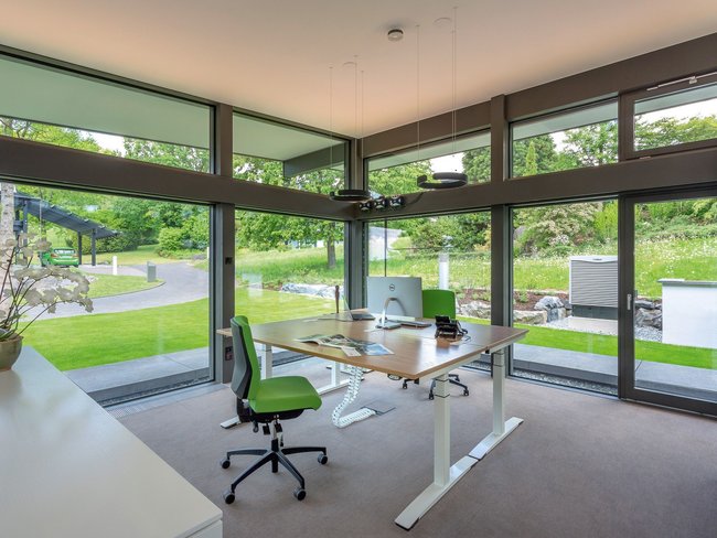 Helles Büro mit grüner Einrichtung und Blick auf die Natur