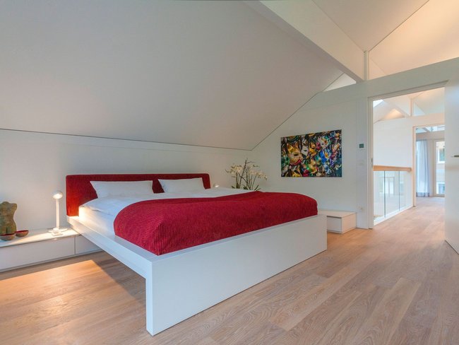 HUF Musterhaus Frankfurt weiss 30 Helles Schlafzimmer mit rotem Bett und zeitgenössischer Kunst
