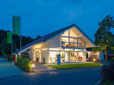 HUF Musterhaus Frankfurt weiss 19 Beleuchtetes modernes Haus in ruhiger Umgebung bei Dämmerung