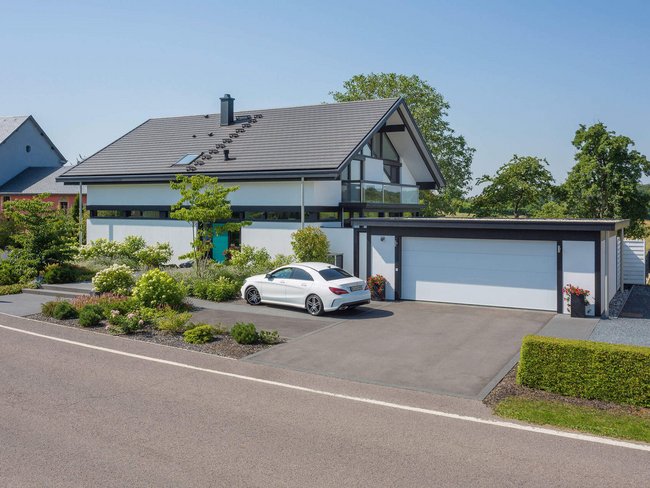 Moderne Architektur eines Wohnhauses mit Garage Stilvolles modernes Haus mit grüner Umgebung und geräumiger Einfahrt