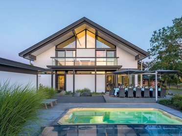 Ein modernes Haus mit großen Fenstern und einem Swimmingpool im Vordergrund