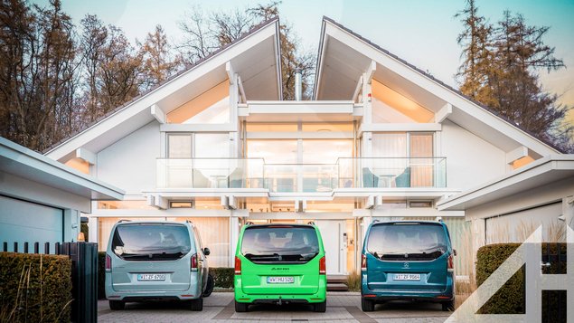 Moderne Wohnarchitektur mit drei Autos in der Einfahrt Futuristisches Haus mit großen Fenstern und drei Autos davor