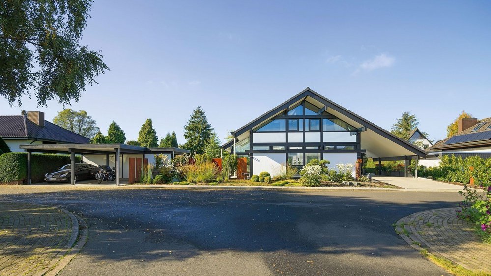 Moderne Architektur eines Fachwerkhauses mit Glas und Holz, umgeben von Garten und Natur