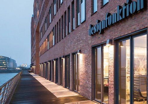 Modernes Gebäude mit Glasfassade und Holzsteg Architekturansicht eines Backsteingebäudes am Wasser mit Sicht auf Eingang