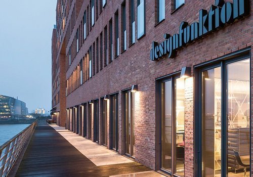 Modernes Gebäude mit Glasfassade und Holzsteg Architekturansicht eines Backsteingebäudes am Wasser mit Sicht auf Eingang