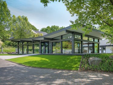 Ein elegantes, modernes Gebäude umgeben von Bäumen und Rasen